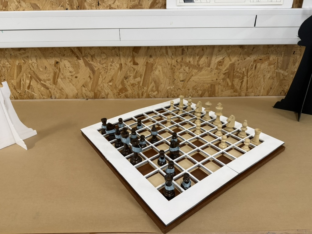 Une grille en relief matérialise les cases ; des rubans différencient les camps.